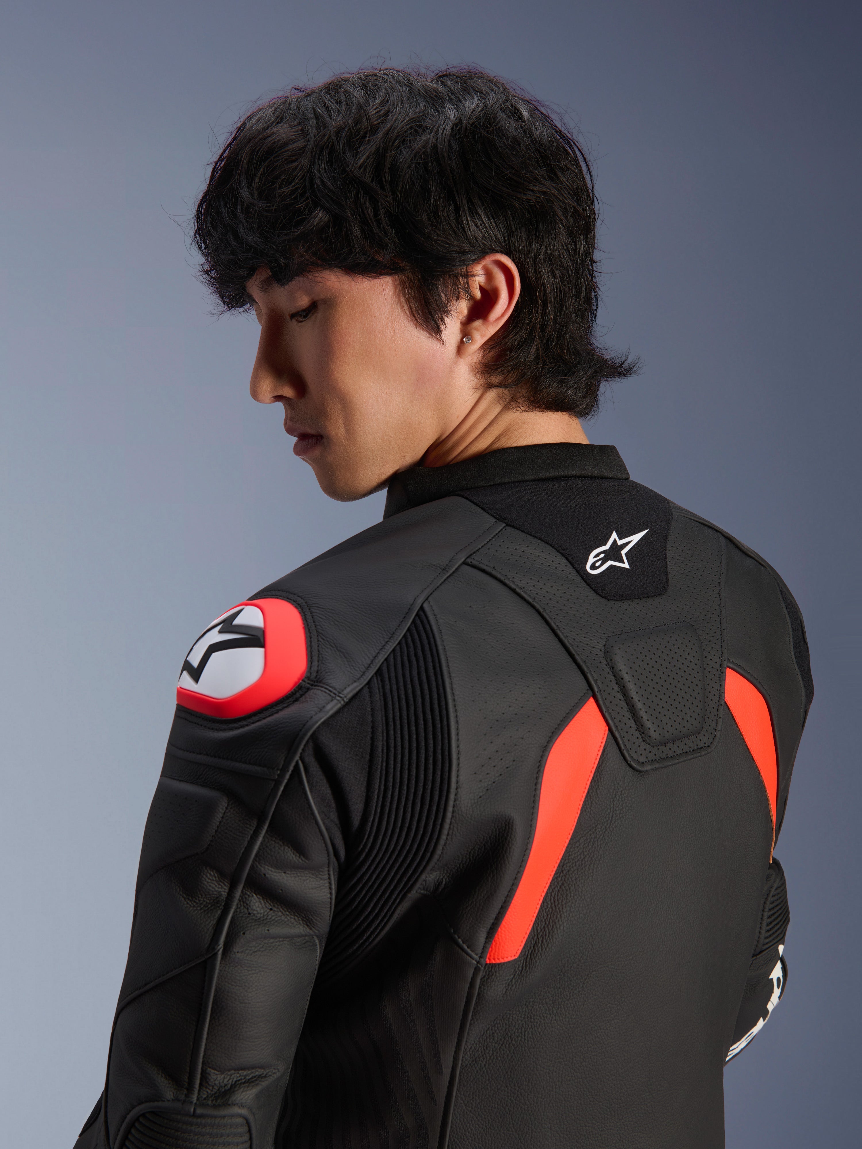 Alpinestars GP Plus R V4 Airflow Leather Jacket, Black with Red Fluo and White accents, close-up view of the back and shoulder on a model, featuring perforated leather zones, Alpinestars logo, and integrated shoulder armor for motorcycle performance.