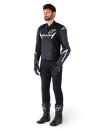 Male model wearing Alpinestars Faster V3 Leather Jacket, Sport Riding Jacket, Black and White, paired with black motorcycle pants, gloves, and boots, featuring white branding and logos, sport-fit silhouette for road racing