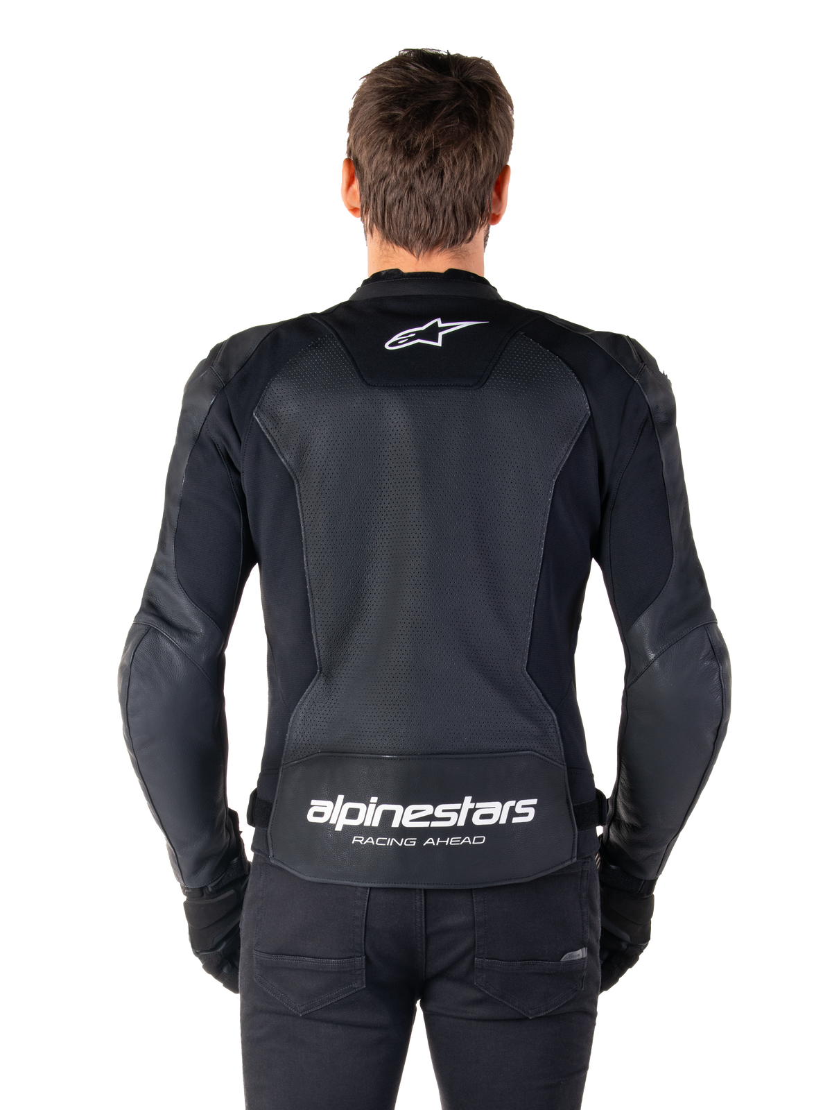 Skórzana kurtka Alpinestars Faster V3 Airflow, czarno-biała, widok motocyklisty od tyłu ukazujący perforowany skórzany panel na plecach zapewniający wentylację, białe logo Alpinestars w górnej części pleców i napis „RACING AHEAD” na dole, sportowa odzież motocyklowa.