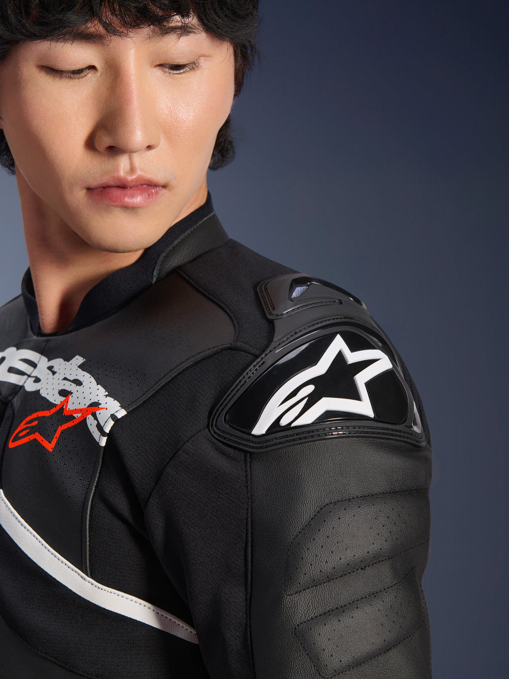 Zbliżenie na skórzaną kurtkę Alpinestars Atem V5 w kolorze czarno-białym, z ochraniaczem ramion DFS RR z białym logo z gwiazdą, perforowaną konstrukcją skórzaną i grafiką na klatce piersiowej inspirowaną wyścigami.