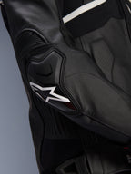Alpinestars Atem V5 Leather Jacket, czarno-biała, zbliżenie na ochraniacz łokcia DFS RR z białym logo gwiazdy, skórzane panele akordeonowe i perforowana tekstura do jazdy sportowej