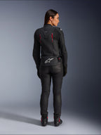 Skórzana kurtka Alpinestars Stella Dusk, widok z tyłu, czarna skóra z akcentami Diva Pink i białymi, białe logo Alpinestars w dolnej części pleców, różowe detale wentylacyjne, noszona z czarnymi spodniami i butami motocyklowymi, sportowa odzież motocyklowa premium dla kobiet