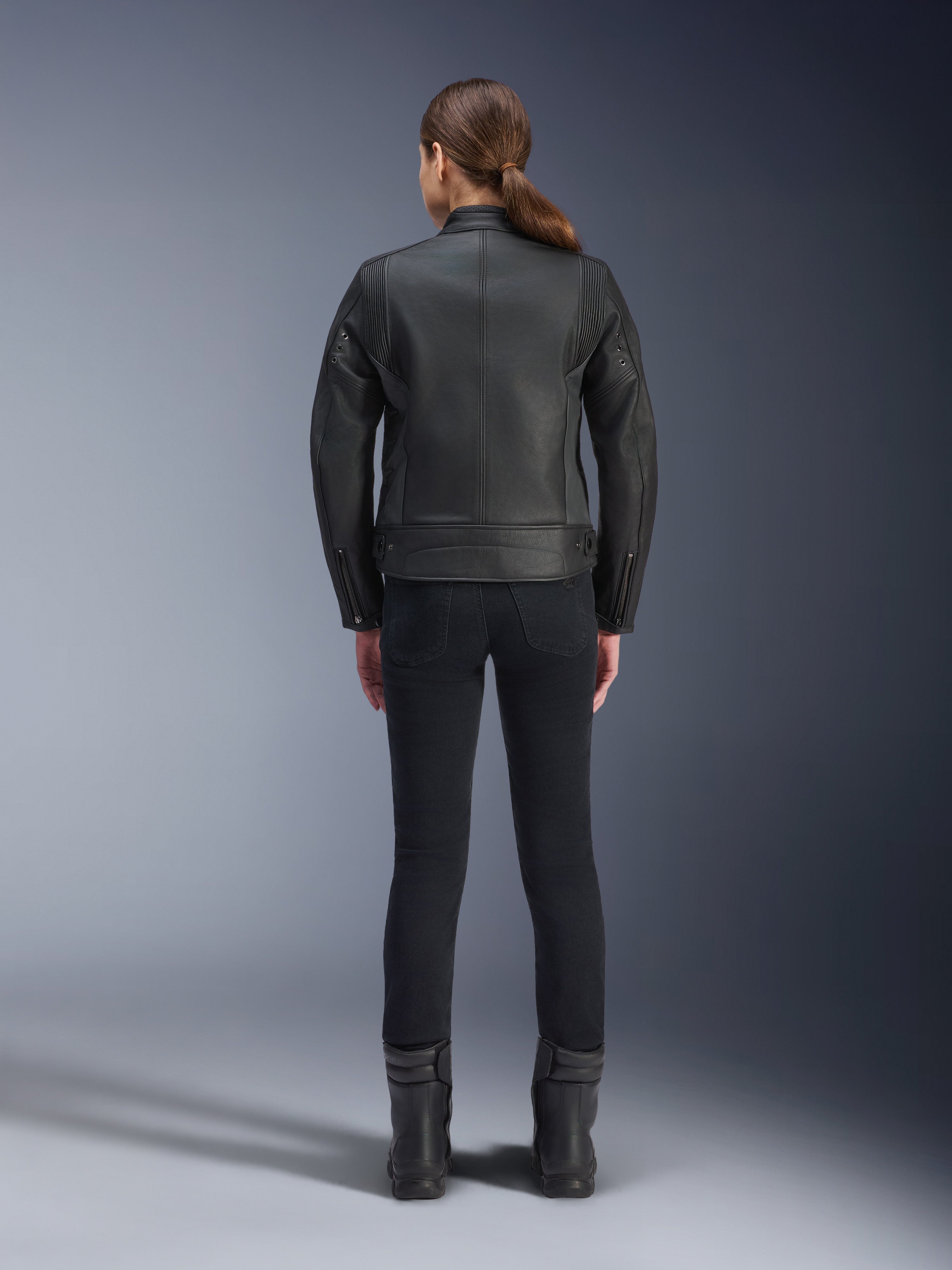 Alpinestars Stella Dyno Leather Jacket, damska kurtka motocyklowa, czarna, widok z tyłu podkreślający dopasowaną konstrukcję ze skóry bydlęcej, minimalistyczny design heritage, noszona z czarnymi spodniami i butami motocyklowymi dla uzyskania miejskiego stylu
