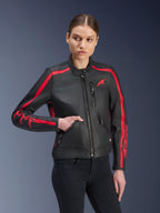 Alpinestars Stella Dyno, damska skórzana kurtka motocyklowa, czarna z czerwonymi pasami wyścigowymi na ramionach i rękawach, prezentowana przez modelkę w czarnych jeansach, wysokiej jakości skóra, design inspirowany stylem heritage do jazdy miejskiej
