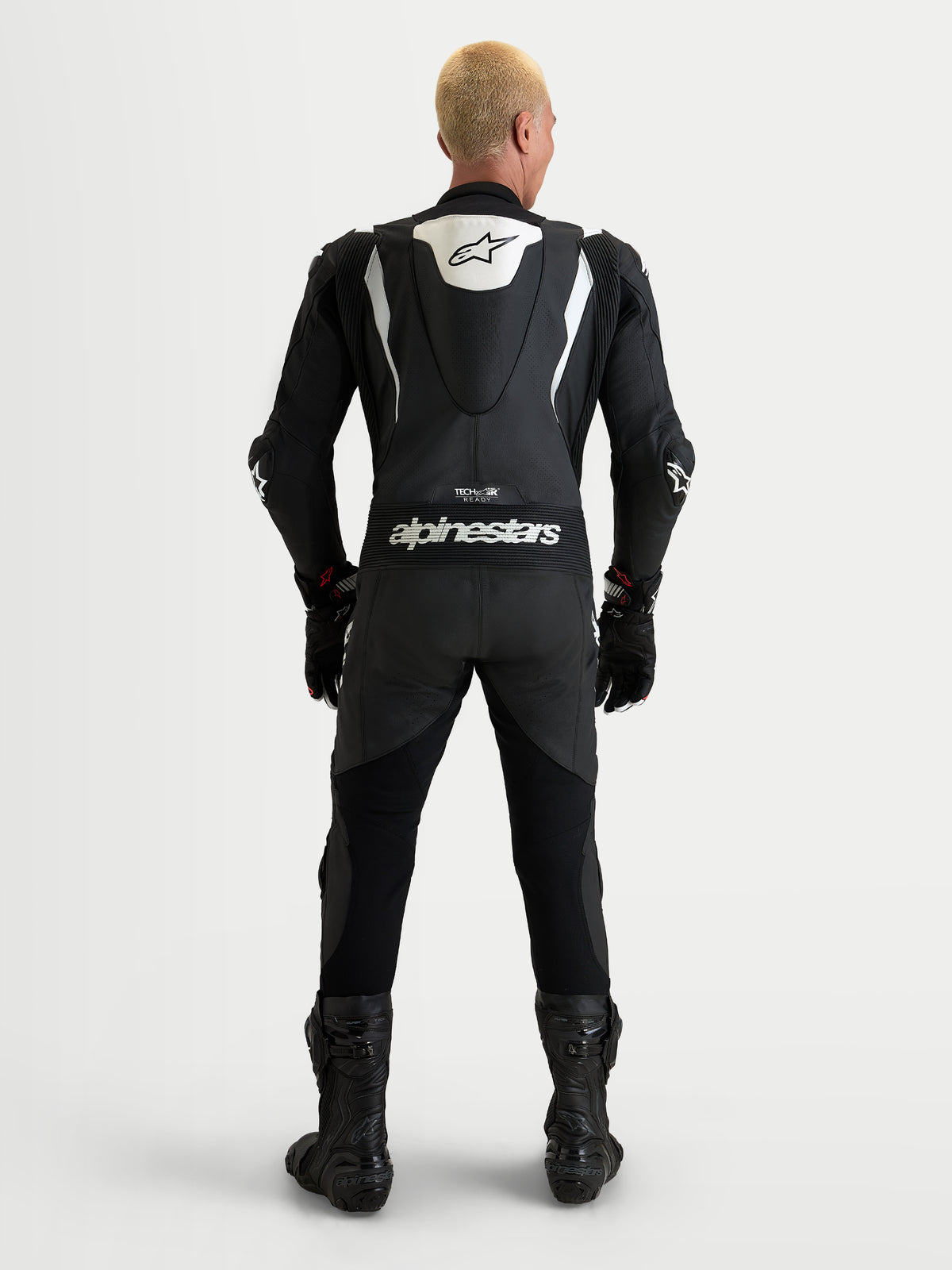 Alpinestars Missile V3, męski jednoczęściowy skórzany kombinezon wyścigowy, czarno-biały, widok z tyłu przedstawiający aerodynamiczny garb i branding Alpinestars