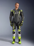 Alpinestars GP Tech V5 One Piece Leather Suit, profesjonalny motocyklowy kombinezon wyścigowy w kolorze czarnym i neonowo-żółtym fluo z białymi akcentami, noszony przez modela z dopasowanymi rękawicami i butami wyścigowymi, o aerodynamicznym designie i z ochronnymi sliderami.