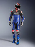 Alpinestars Yamaha GP-R7, jednoczęściowy kombinezon skórzany, motocyklowy kombinezon wyścigowy, kolor metaliczny niebieski i czarny z czerwonymi i białymi akcentami, logotypy Yamaha i GYTR, noszony z dopasowanym kaskiem, rękawicami wyścigowymi i niebieskimi butami, profesjonalny sprzęt wyczynowy