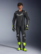 Alpinestars GP Force V2 Leather Suit, jednoczęściowy czarny motocyklowy kombinezon wyścigowy, noszony z neonowożółtymi butami i rękawicami, z białymi logo i perforowaną skórą, dopasowany krój na dni torowe