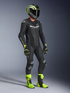 Skórzany kombinezon Alpinestars GP Force V2, jednoczęściowy kombinezon motocyklowy, czarny z białym brandingiem, noszony z pasującym neonowo-żółtym i czarnym kaskiem, rękawicami i butami, wysokowydajny sprzęt wyścigowy do jazdy torowej i sportowej