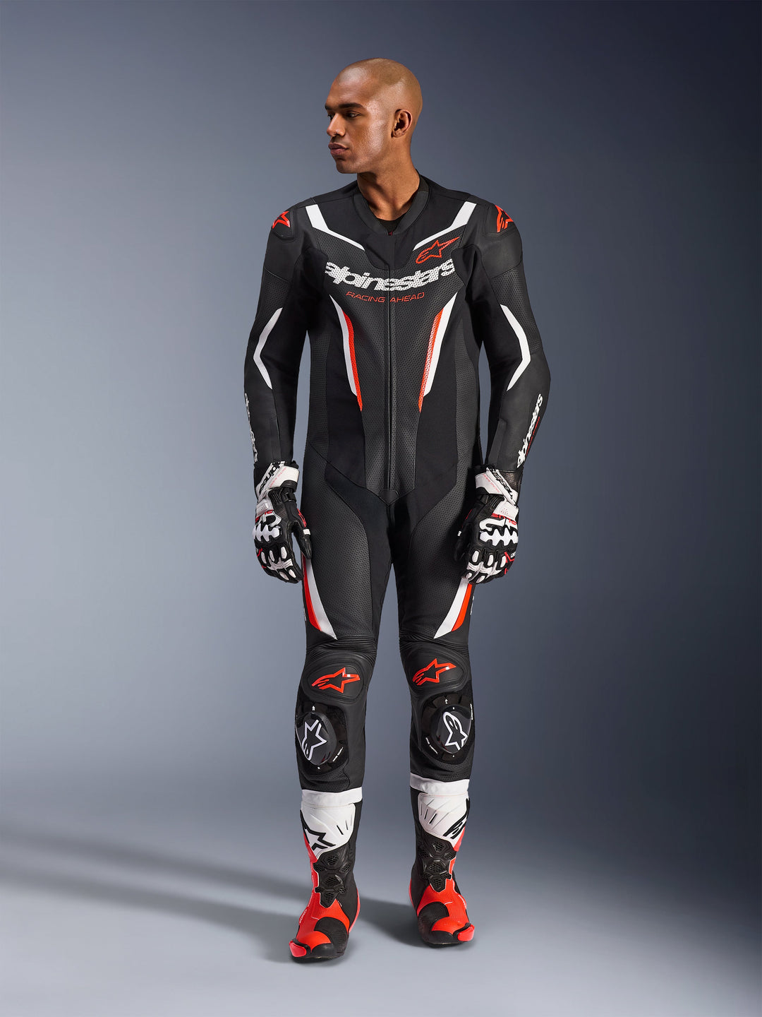 Alpinestars GP Force V2 Leather Suit - 1Piece, czarny, biały i czerwony fluo, widok całej sylwetki męskiego modelu w profesjonalnym stroju wyścigowym z dopasowanymi rękawicami i butami, z perforowanymi panelami skórzanymi i ochronnymi ślizgaczami kolan