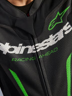 Alpinestars GP Force V2 Leather Suit - 1Piece, zbliżenie na klatkę piersiową, czarna perforowana skóra z białym brandingiem Alpinestars, zielony napis „RACING AHEAD” i zielone akcenty