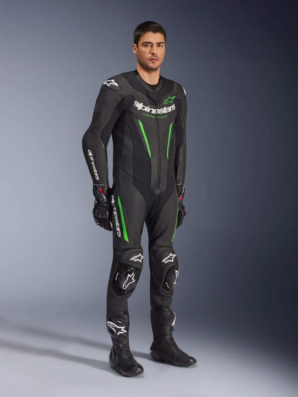 Alpinestars GP Force V2 Leather Suit 1-Piece, czarno-zielony, pełny strój wyścigowy z czarnymi rękawicami i butami, posiada perforowane panele skórzane, białe logo Alpinestars i zintegrowane slidery kolan, profesjonalny kombinezon torowy