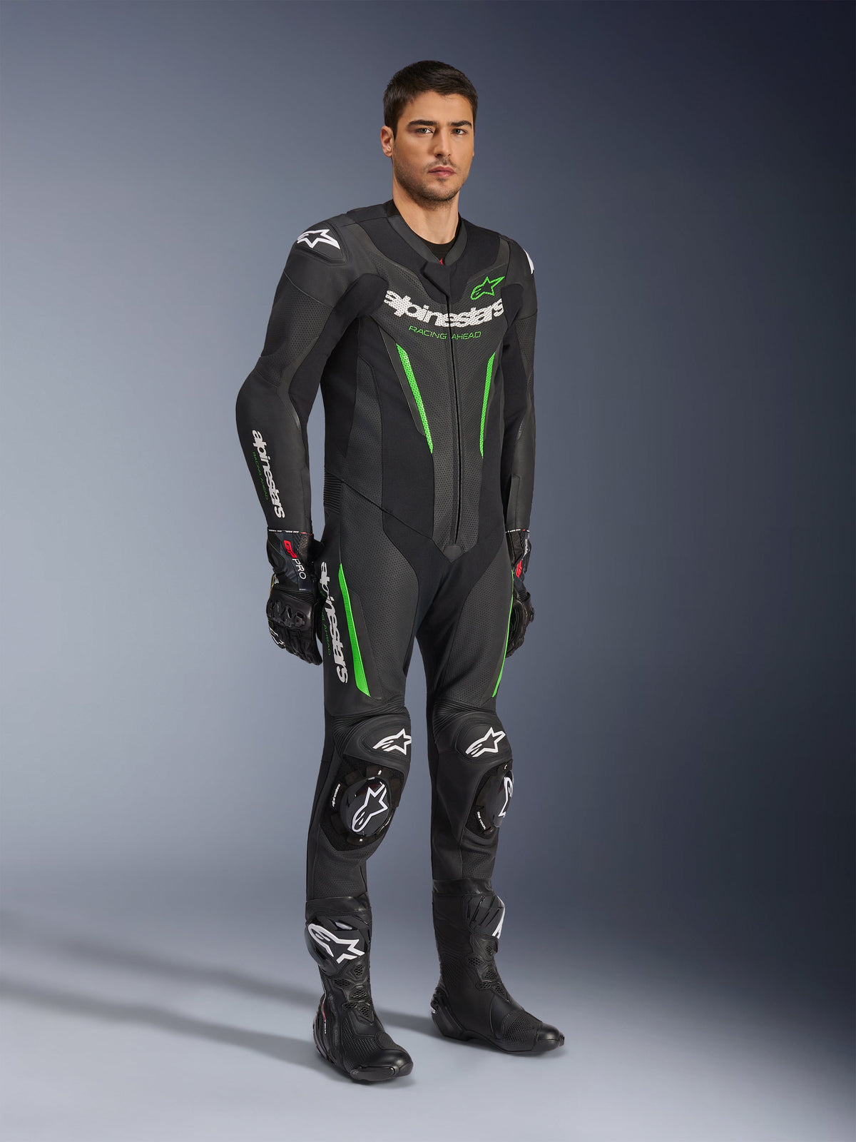 Alpinestars GP Force V2 Leather Suit 1-Piece, czarno-zielony, pełny strój wyścigowy z czarnymi rękawicami i butami, posiada perforowane panele skórzane, białe logo Alpinestars i zintegrowane slidery kolan, profesjonalny kombinezon torowy