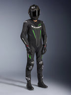 Jednoczęściowy skórzany kombinezon Alpinestars GP Force V2, czarno-zielony, noszony z dopasowanym czarnym kaskiem, rękawicami wyścigowymi i butami, z jasnozielonymi akcentami i wyraźnym białym brandingiem Alpinestars, profesjonalna odzież do jazdy torowej i sportowej
