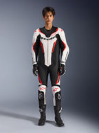 Alpinestars GP Force V2 Leather Suit - 1Piece, biało-czarno-czerwony fluorescencyjny, jednoczęściowy skórzany kombinezon motocyklowy, widok z przodu na modelu, z perforowanymi panelami i czerwonymi akcentami, wyraźne logo Alpinestars na klatce piersiowej, w stylizacji z profesjonalnymi butami i rękawicami wyścigowymi