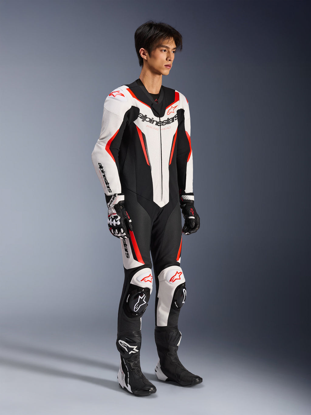 Alpinestars GP Force V2 Leather Suit - 1Piece, jednoczęściowy wyścigowy kombinezon motocyklowy, biało-czarno-czerwony fluo, noszony z pasującymi rękawicami i butami, perforowana skóra, wyraźny branding Alpinestars, aerodynamiczna konstrukcja zapewniająca wydajność na torze