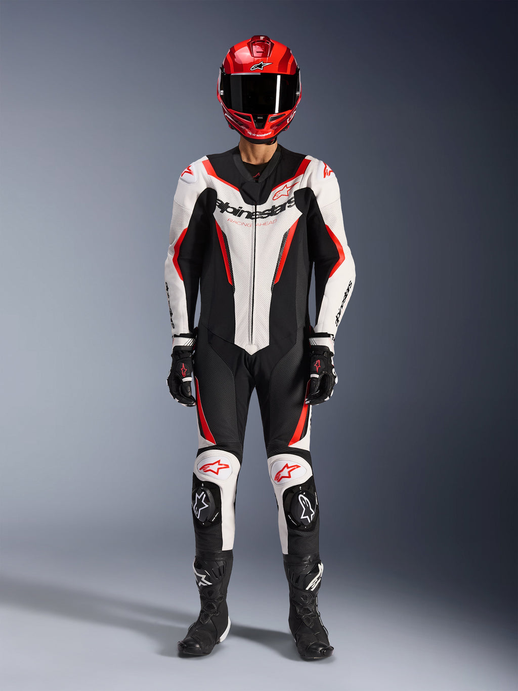 Alpinestars GP Force V2 Leather Suit - 1-częściowy, biało-czarno-czerwony fluo, kompletny strój wyścigowy zawierający czerwony kask, czarne rękawice i buty, o aerodynamicznym designie z logo Alpinestars na klatce piersiowej i kolanach