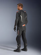 Alpinestars GP Force V2 2-Piece Leather Suit, dwuczęściowy kombinezon skórzany, czarny z białymi i czerwonymi akcentami fluo, widok z tyłu na modelu, aerodynamiczny garb, perforowane panele skórzane i wyraźne logo Alpinestars, czarne buty i rękawice wyścigowe.