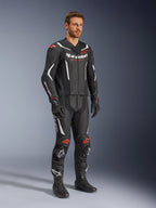 Alpinestars GP Force V2 2-Piece Leather Suit, czarny, biały i czerwony fluo, noszony przez modela z czarnymi butami i rękawicami wyścigowymi, z perforowanymi panelami skórzanymi, białymi akcentami aerodynamicznymi i logotypami w kolorze czerwonym fluo na ramionach i kolanach, profesjonalna odzież motocyklowa