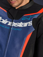 Alpinestars GP Force V2 Leather Suit, 2-częściowy kombinezon skórzany, zbliżenie na klatkę piersiową, perforowana niebieska skóra z białym logo i napisem „RACING AHEAD”, akcenty Red Fluo i czarne panele, profesjonalna sportowa odzież motocyklowa