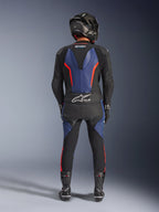 Alpinestars GP Force V2 Leather Suit 2-Piece, Black Blue Red Fluo, pełny widok z tyłu na motocyklistę w pełnym stroju wyścigowym, niebieskie panele skórzane na plecach i nogach z fluorescencyjnymi czerwonymi akcentami, logo Tech-Air® Ready na dolnej części pleców, kask z włókna węglowego, czarne rękawice i buty wyścigowe.