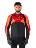 Alpinestars T-Jaws V4 Waterproof Jacket, sportowa tekstylna kurtka motocyklowa, czarna z akcentami czerwonymi fluo i ciemnoczerwonymi, noszona przez modela z dopasowanymi rękawicami, techniczna odzież motocyklowa z wyraźnym logo gwiazdy na piersi