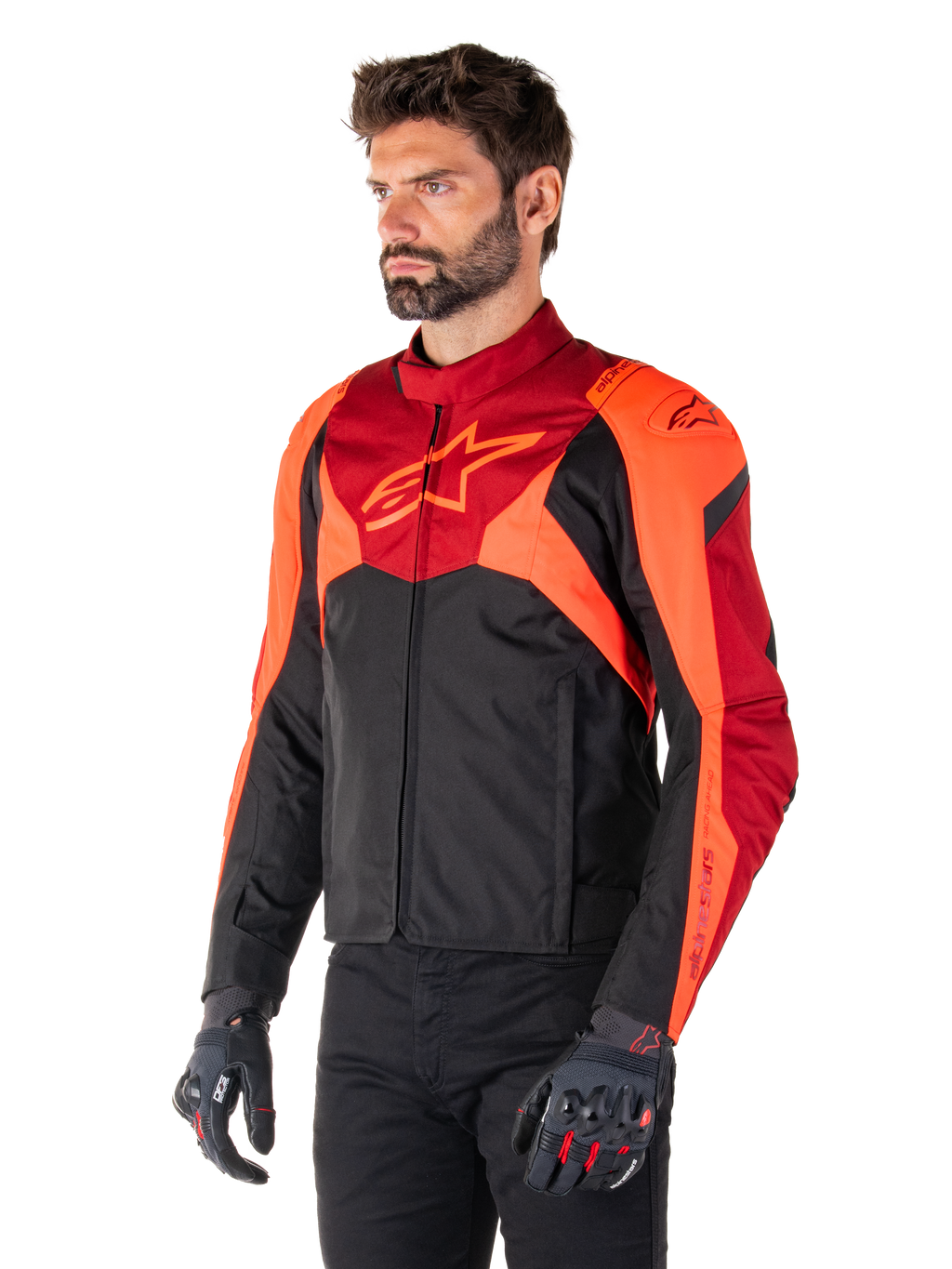 Kurtka Alpinestars T-Jaws V4 Waterproof, czarna, neonowa czerwona i ciemnoczerwona, noszona przez modela w czarnych spodniach i rękawicach motocyklowych, agresywna sportowa sylwetka z logo Alpinestars na klatce piersiowej, ujęcie 3/4