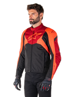 Kurtka Alpinestars T-Jaws V4 Waterproof, czarna, neonowa czerwona i ciemnoczerwona, noszona przez modela w czarnych spodniach i rękawicach motocyklowych, agresywna sportowa sylwetka z logo Alpinestars na klatce piersiowej, ujęcie 3/4