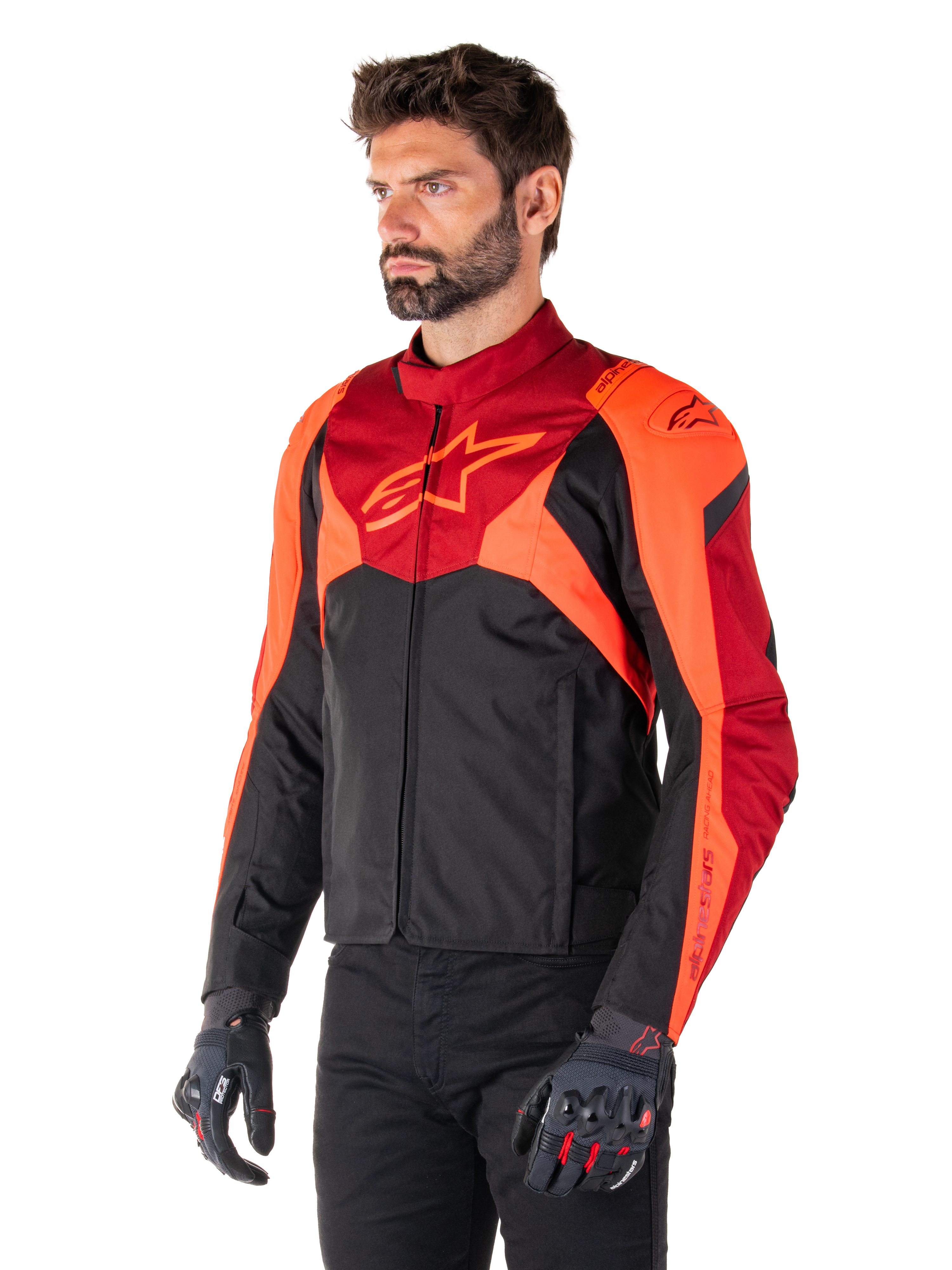 Kurtka Alpinestars T-Jaws V4 Waterproof, czarna, neonowa czerwona i ciemnoczerwona, noszona przez modela w czarnych spodniach i rękawicach motocyklowych, agresywna sportowa sylwetka z logo Alpinestars na klatce piersiowej, ujęcie 3/4
