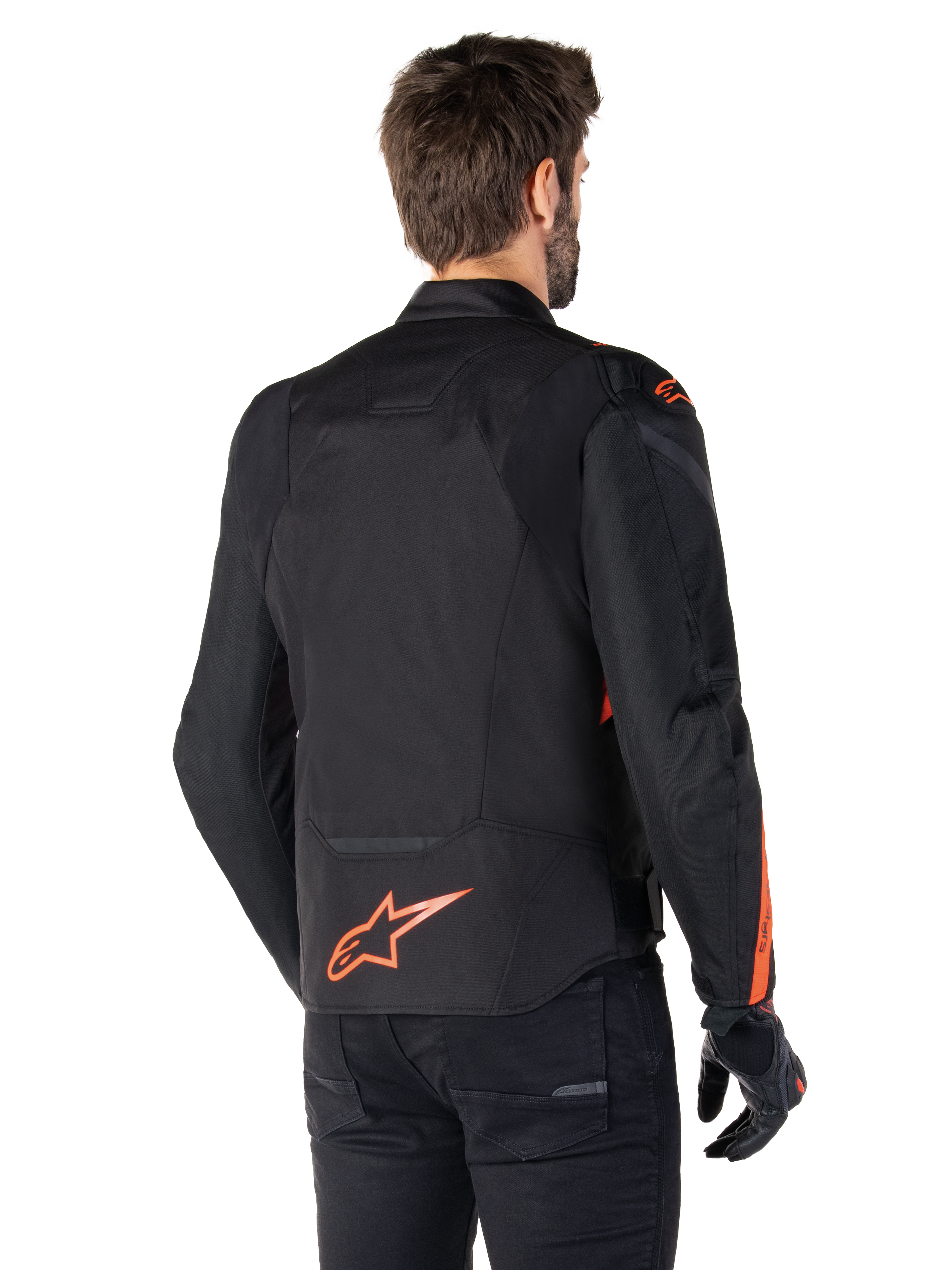 Male model wearing the Alpinestars T-Jaws V4 Waterproof Jacket from the back, Black with Red Fluo accents, featuring a red fluo logo on the lower back and accents on the shoulders and sleeves, sport motorcycle riding gear.