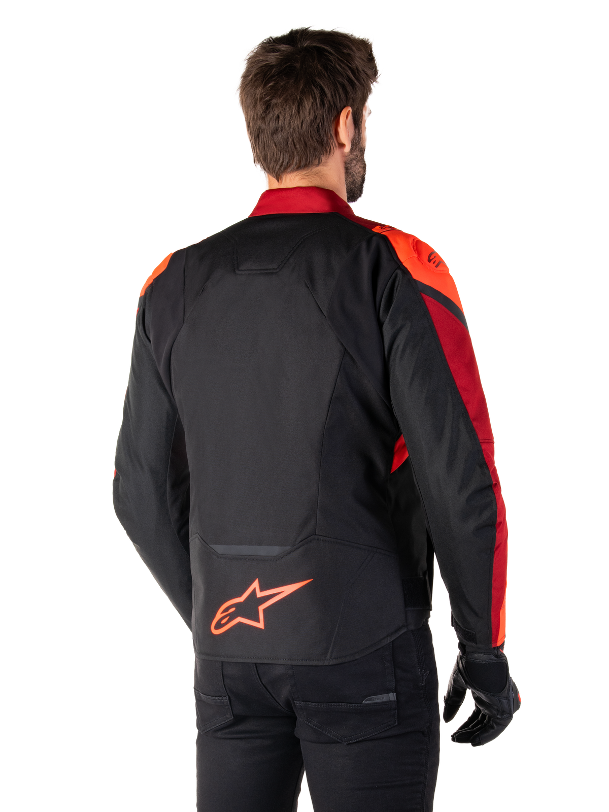 Widok z tyłu na mężczyznę ubranego w kurtkę Alpinestars T-Jaws V4 Waterproof w kolorze Black Red Fluo Dark Red, z jaskrawoczerwonymi akcentami na ramionach i rękawach, neonowym czerwonym logo Alpinestars na dole pleców, w zestawieniu z czarnymi spodniami i rękawicami.