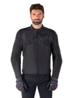 Kurtka motocyklowa Alpinestars T-Jaws V4 Waterproof, czarna sportowa kurtka motocyklowa, prezentowana na mężczyźnie w czarnych rękawicach z czerwonymi akcentami, wzmocnione barki i ramiona, elegancki design z subtelnym logo na klatce piersiowej, tekstylna odzież motocyklowa na każdą pogodę