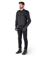 Męski model ubrany w wodoodporną kurtkę Alpinestars T-Jaws V4 w kolorze czarnym, w zestawieniu z czarnymi spodniami motocyklowymi, czarnymi rękawicami z czerwonymi akcentami oraz czarnymi butami motocyklowymi; kurtka o dopasowanym sportowym kroju z subtelnym brandingiem, na białym tle.