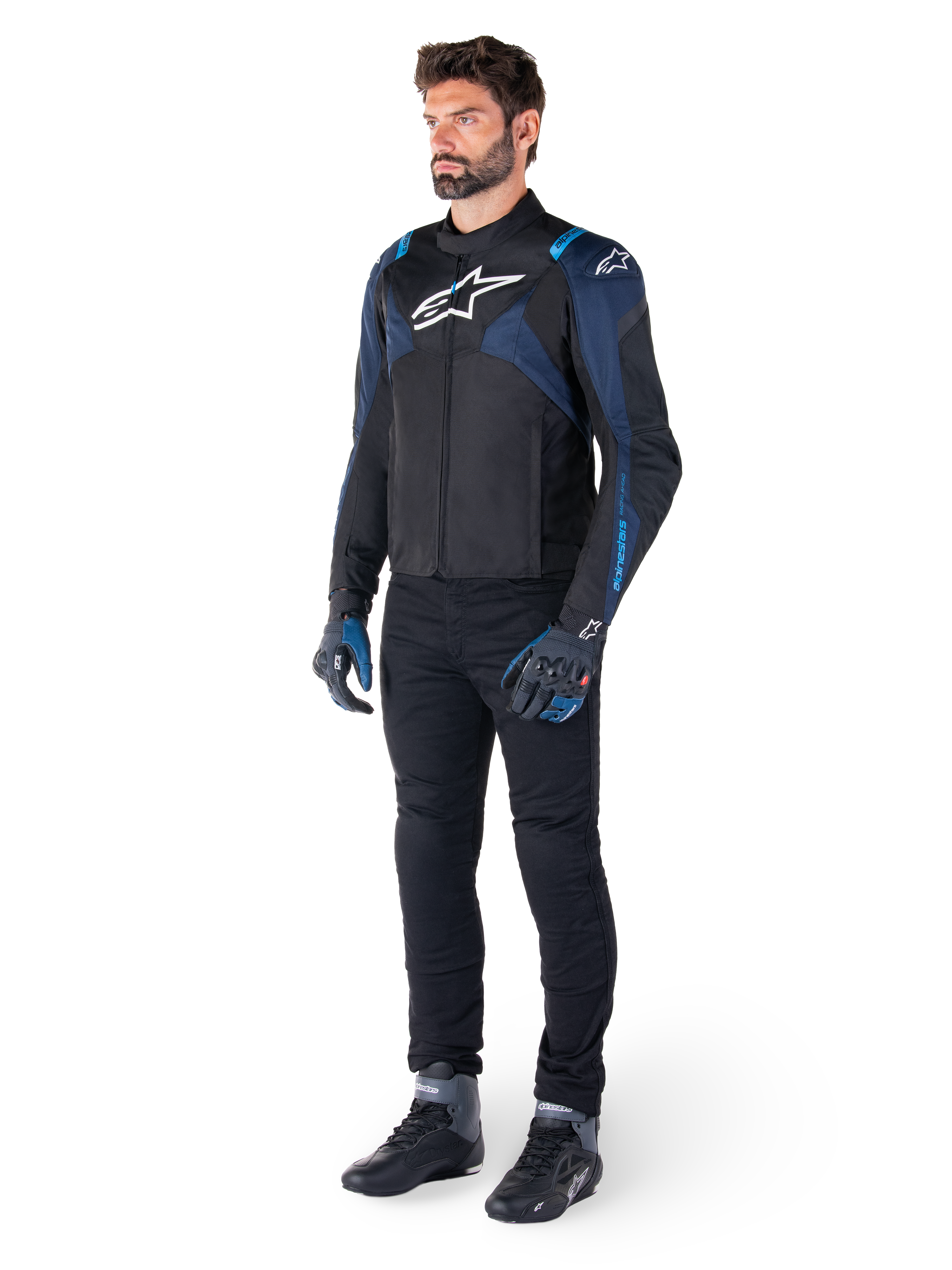 Alpinestars T-Jaws V4 Waterproof Jacket in Black, Dark Blue, and Blithe Blue, worn by a model with black motorcycle pants and riding boots, featuring white Alpinestars logo on chest and blue shoulder accents, sport-fit riding gear.