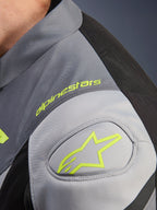 Wodoodporna kurtka Alpinestars T-Jaws V4, detal ramienia z neonowożółtym logo i logotypem Alpinestars, techniczny materiał tekstylny w kolorach Black Ice Gray i Dark Gray, wzmocnienie ramienia GP Lite