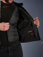 Widok wnętrza kurtki Alpinestars T-Jaws V4 Waterproof, prezentujący wyjmowaną czarną pikowaną podszewkę termiczną i wodoodporną kieszeń wewnętrzną z czerwoną etykietą, siatkowa podszewka, konstrukcja motocyklowa klasy premium.