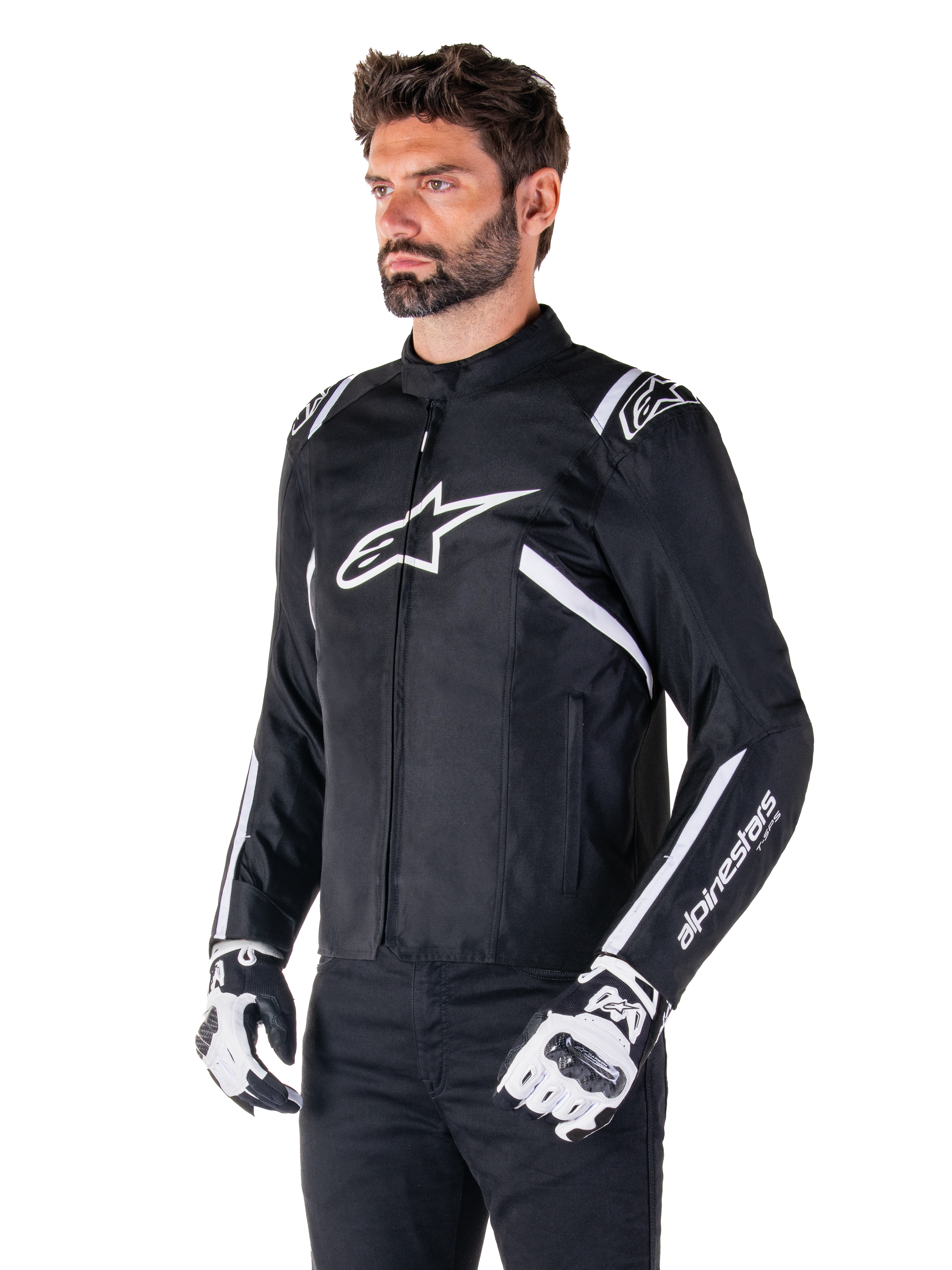 Kurtka Alpinestars T-SPS V2 Waterproof, czarno-biała, noszona przez modela w pasujących rękawicach motocyklowych, tekstylna kurtka o sportowym kroju z białym logo Alpinestars na piersi i ramionach, branding "alpinestars T-SPS" na rękawie, stylowa odzież motocyklowa inspirowana wyścigami