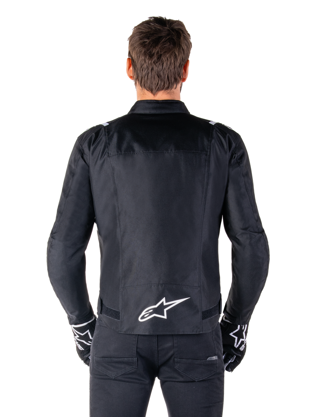 Alpinestars T-SPS V2 Waterproof Jacket, czarno-biała, widok z tyłu z białym logo Alpinestars na dole pleców, zestaw z czarnymi spodniami i rękawicami, tekstylna kurtka motocyklowa o sportowym kroju
