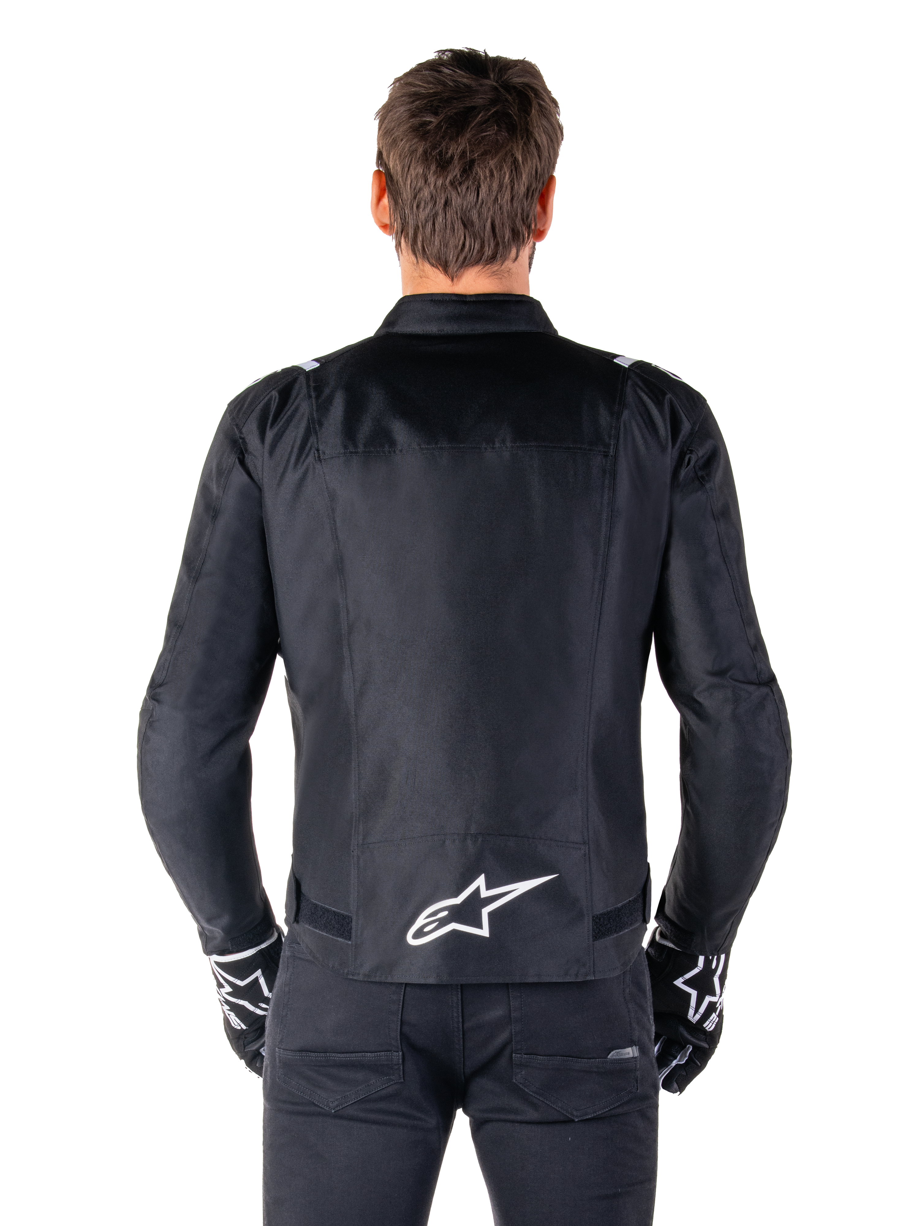 Alpinestars T-SPS V2 Waterproof Jacket, czarno-biała, widok z tyłu z białym logo Alpinestars na dole pleców, zestaw z czarnymi spodniami i rękawicami, tekstylna kurtka motocyklowa o sportowym kroju