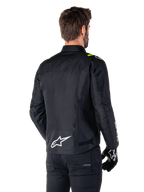 Alpinestars T-SPS V2 Waterproof Jacket, Black White Yellow Fluo, rear view of male model wearing the textile motorcycle jacket, featuring a white logo on the lower back and yellow fluo accents on the shoulders, paired with black pants and gloves.