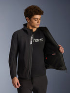 Alpinestars Aeroshell Waterproof Jacket, czarna motocyklowa kurtka typu softshell, rozpięta, prezentująca wewnętrzną kieszeń i podszewkę, noszona przez modela z czarnym t-shirtem z logo, fason z kapturem do codziennej jazdy miejskiej w stylu street style.
