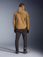 Wodoodporna kurtka Alpinestars Aeroshell, kolor Dark Khaki Black Orange Fluo, widok od tyłu na mężczyznę w kurtce softshell z kapturem, czarne lamówki i pomarańczowe logo, czarne spodnie techniczne i rękawice