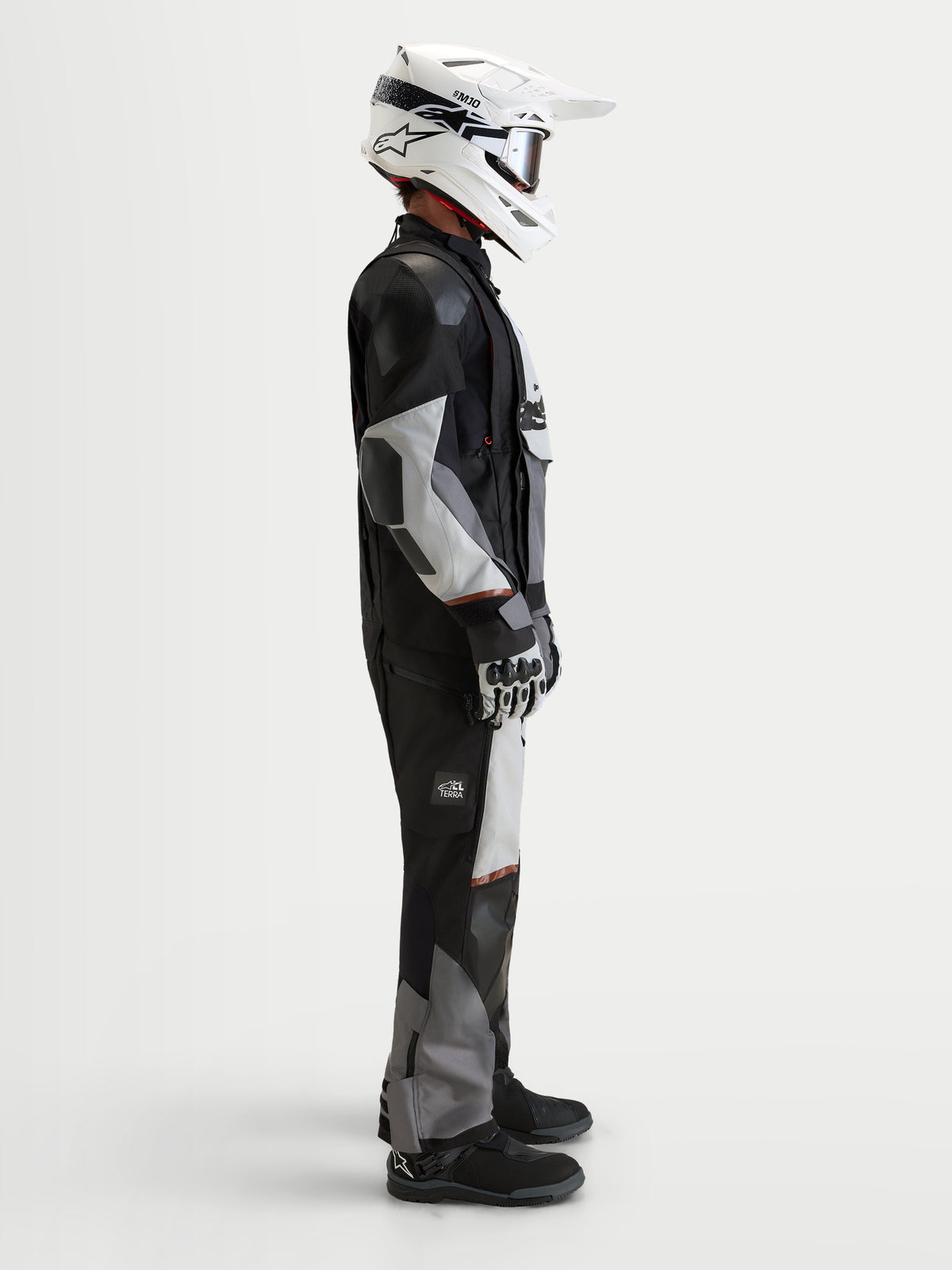 Alpinestars Harok V2 Drystar, męska kurtka motocyklowa turystyczna all-terrain, ciemnoszara, jasnoszara i czarna, widok z boku w studiu z kaskiem i odzieżą adventure