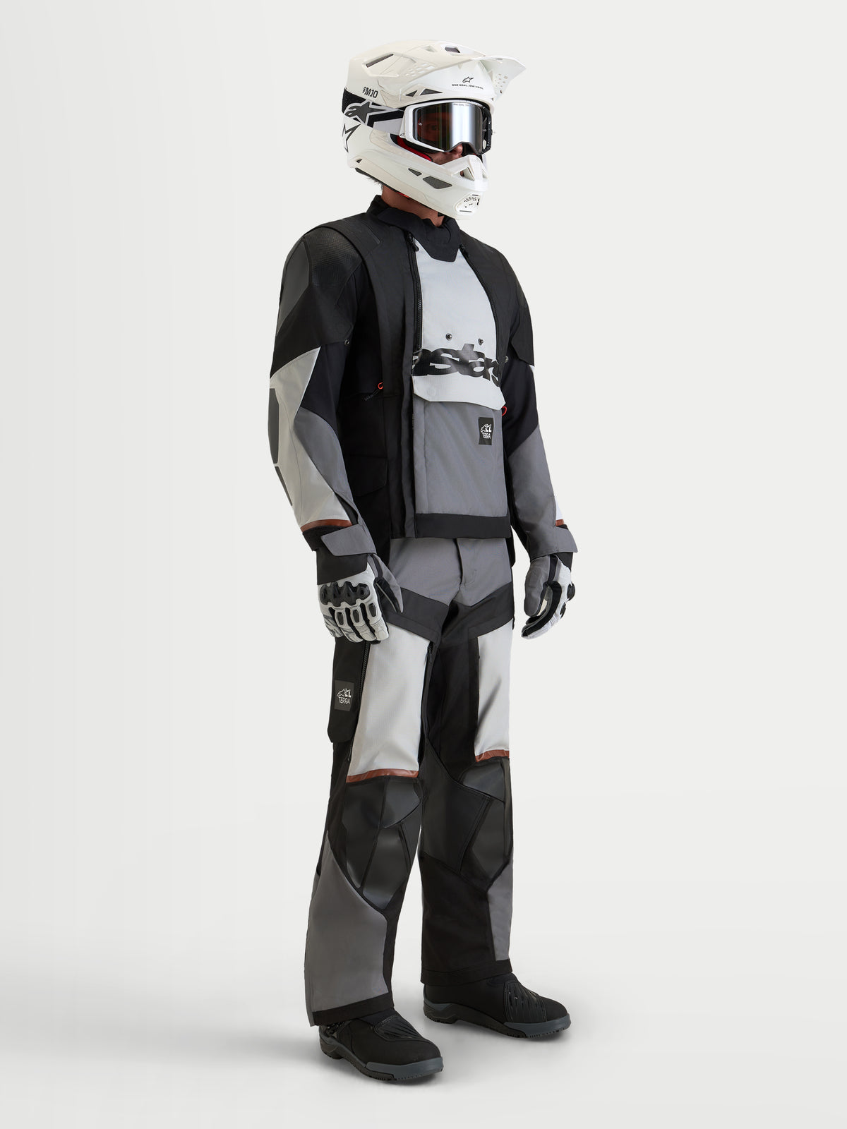 Alpinestars Harok V2 Drystar Gear Set, kurtka i spodnie motocyklowe adventure w kolorze czarnym i jasnoszarym, na modelu w białym kasku i pasujących rękawicach