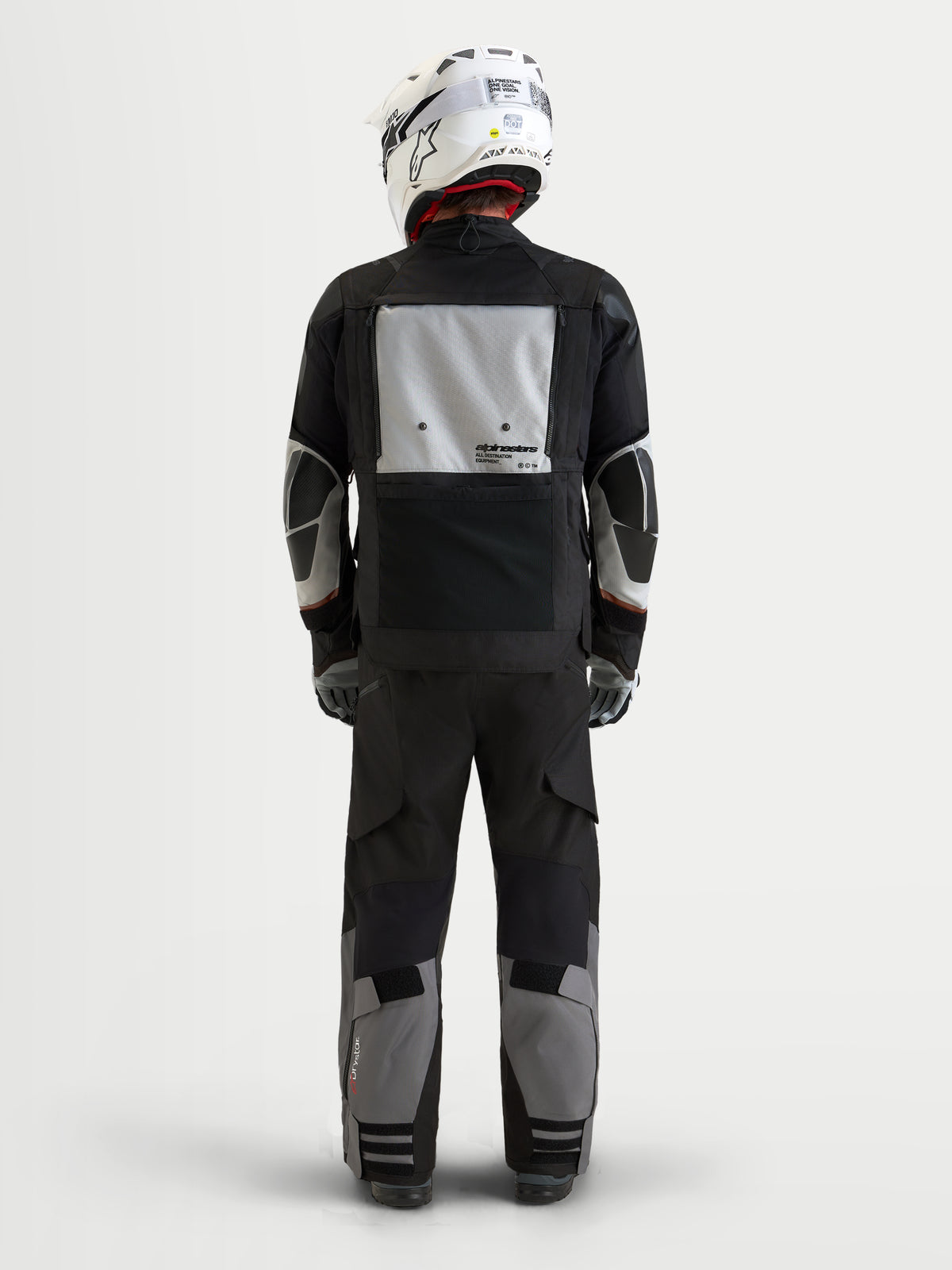 Alpinestars Harok V2 Drystar Gear Set, czarno-szary motocyklowy zestaw turystyczny kurtki i spodni, widok z tyłu na model w pasującym białym kasku, wodoodporna konstrukcja z cechami do jazdy adventure