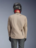 Kurtka Alpinestars Borrego Drystar®, motocyklowa kurtka adventure, kolor Warm Gray, widok z tyłu przedstawiający zamek tylnej komory oraz branding Alpinestars, noszona z czarnym kaskiem i grafitowymi spodniami motocyklowymi