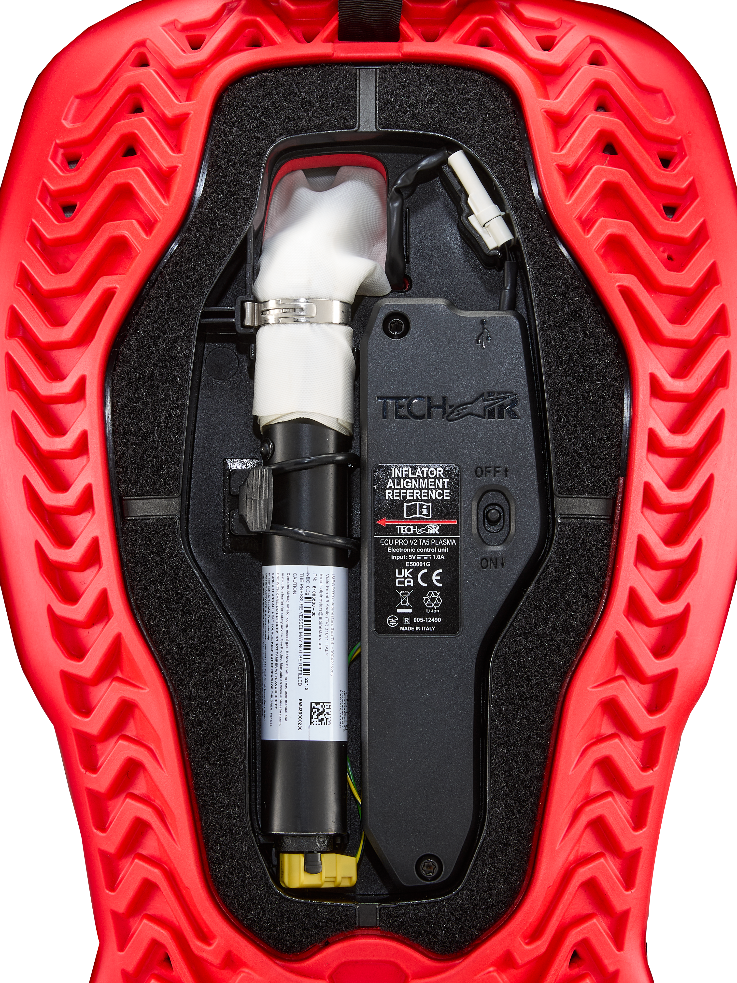 Alpinestars Tech-Air® 5 Plasma, zapasowy nabój do poduszki powietrznej, akcesorium do systemu airbag, czerwono-czarny, zbliżenie na komponenty wewnętrzne: biały inflator z argonem, srebrna klamra, jednostka sterująca z przełącznikiem ON/OFF, czerwona obudowa o falistej, żebrowanej strukturze