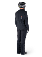 Kurtka Alpinestars AMT-8 Stretch Drystar® XF, czarna, widok z tyłu motocyklisty ubranego w kurtkę, pasujące czarne spodnie i czarny kask, z logo „Alpinestars Motion Technology” na plecach, techniczny elastyczny materiał do jazdy motocyklowej typu adventure
