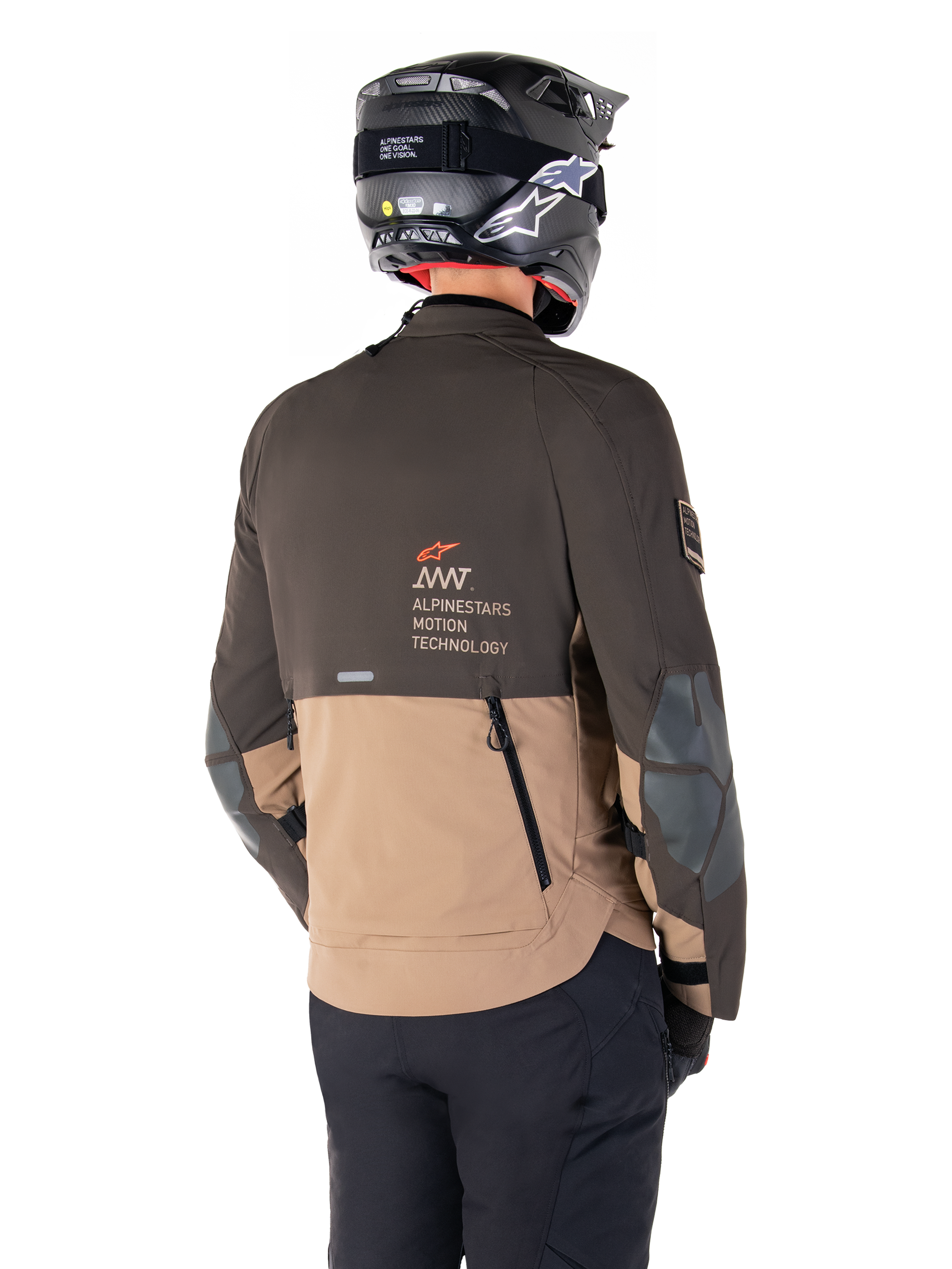 Kurtka Alpinestars AMT-8 Stretch Drystar® XF, motocyklowa kurtka adventure, ciemnobrązowa i ciemne khaki, widok z tyłu prezentujący branding AMT Alpinestars Motion Technology, dwukolorowa konstrukcja tekstylna z tylnymi zamkami wentylacyjnymi i wylotem powietrza o konstrukcji dachówkowej, zestawiona z czarnym kaskiem i spodniami motocyklowymi