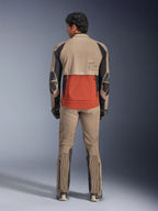 Kurtka Alpinestars AMT-8 Stretch Drystar® XF, Walnut Rust Black, widok z tyłu na motocykliście w pasujących spodniach adventure i rękawicach, z charakterystycznym rdzawym panelem tylnym, orzechowymi górnymi sekcjami i czarnymi elastycznymi wstawkami, zaprojektowana do dalekiej turystyki.
